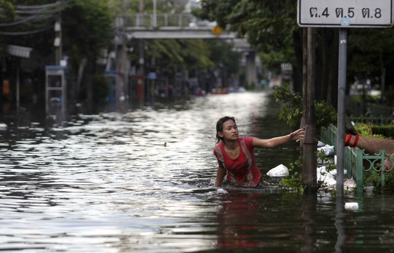 A Thai woman struggles to wade through a flooded street in Bangkok, Thailand, Friday, Oct. 28, 2011. The main river coursing through Thailand's capital swelled to record highs Friday, briefly flooding riverside buildings and an ornate royal complex at high tide amid fears that flood defenses could break and swamp the heart of the city. (AP Photo/Altaf Qadri)