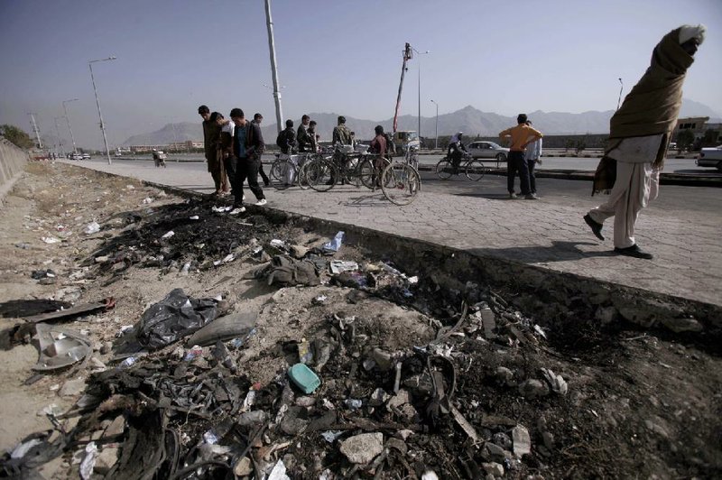 Afghans gather Sunday at the site of Saturday’s suicide car bombing in Kabul. 