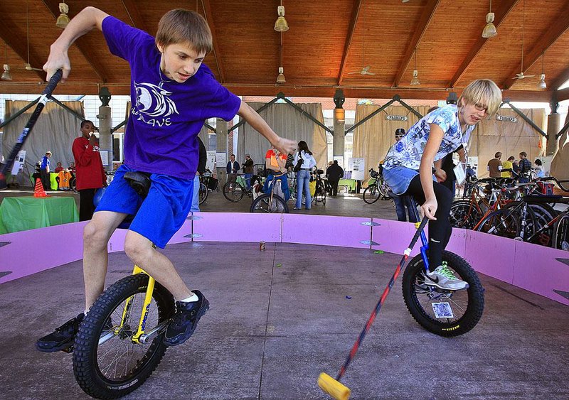 Nick Vire (left) and Mandolin Harris ride unicycles while demonstrating a game of Knife Fight, a derivative of bike polo, during the Mayor’s Car-Free Challenge Learning Fair held Sunday afternoon at the Little Rock River Market. The event included tips and information for walkers, cyclists and bus riders for parking their gasoline-fueled personal vehicles for the week starting Saturday and ending Nov. 11. 