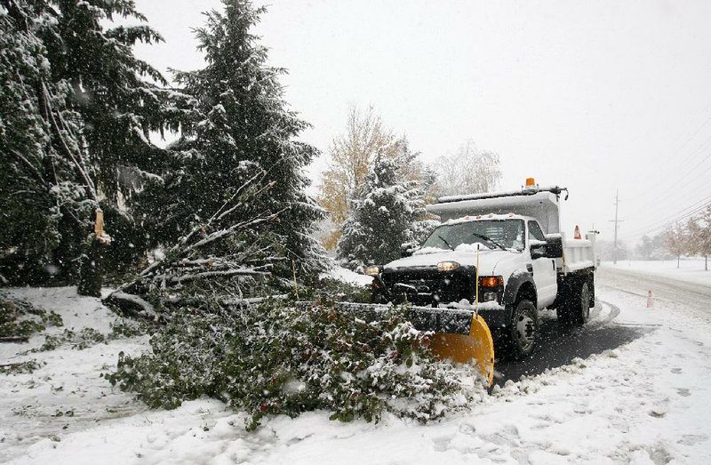 A crew from the Greenwich Twp. Dept. of Public Works clears a fallen branch blocking Greenwich St. in Stewartsville, N.J., Saturday Oct. 29, 2011. An unusual October storm dumped wet heavy snow across much of the northeast. (AP Photo/Rich Schultz)