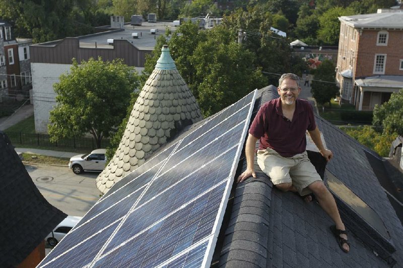 Tim Johnson sits on his roof next to solar panels that have cut the electricity bill at his Philadelphia home by about $20 to $30 per month. 