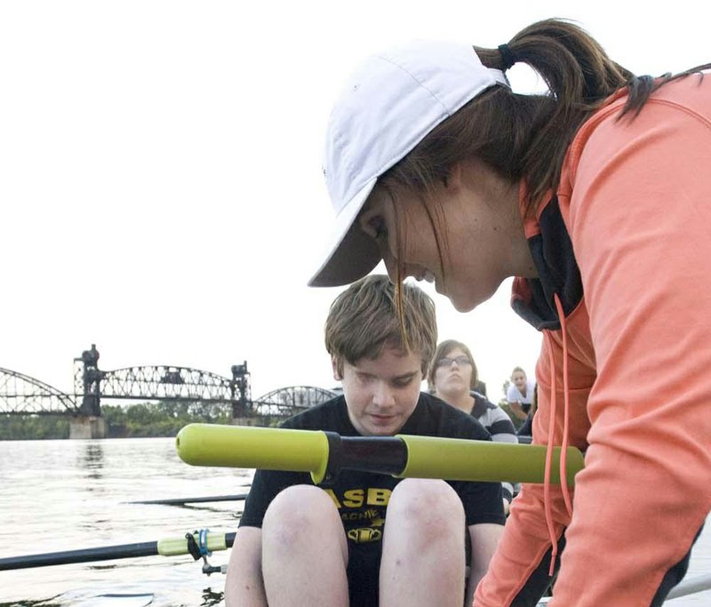 Maeve Andrews, an occupational therapy student from UCA, helps Kyler Reschke, a student from The Arkansas School for the Blind and Visually Impaired, get his feet secured on the foot plate in the racing shell. The Arkansas Boathouse Club held a rowing workshop for visually impaired students. 