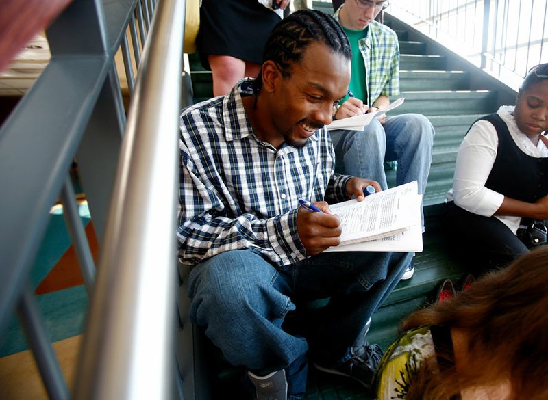 Moe Ayyubi (cq) of Rogers fills out forms while sitting on steps inside the Shewmaker Center for Workforce Technologies for the Crystal Bridges Museum of American Art job fair on the Bentonville campus of NWACC on Thursday, Sept. 1, 2011. Ayyubi was interested in a position as a prep cook.