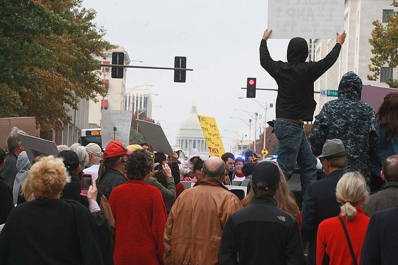   About 100 protesters from the Occupy Little Rock group march up Capitol Ave. at Broadway St. in Little Rock Saturday. They started in the River Market and walked through downtown stopping at banks along the way to "mourn" the passing of our economy.