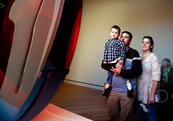 Gregory and Heather Meister and their son Isaac, 3, of Bella Vista consider Frederick Eversley’s Big Red Lens on Friday at Crystal Bridges Museum of American Art in Bentonville.