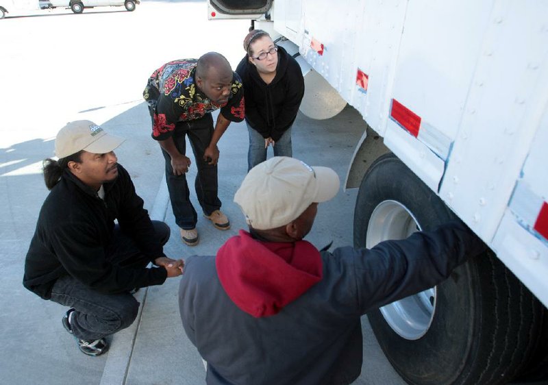 Diesel Driving Academy instructor Vernon Hamilton (bottom) talks with students Tyrone Shavers (left), Ricardo Brewer and Brittney Trent as they pick up a truckload of food Thursday morning at the Arkansas Foodbank in Little Rock. 