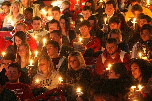 Arkansas Democrat-Gazette/WILLIAM MOORE -- Students hold candles during a vigil for Garrett Uekman Monday, November 21, 2011 at Bud Walton Arena in Fayetteville.