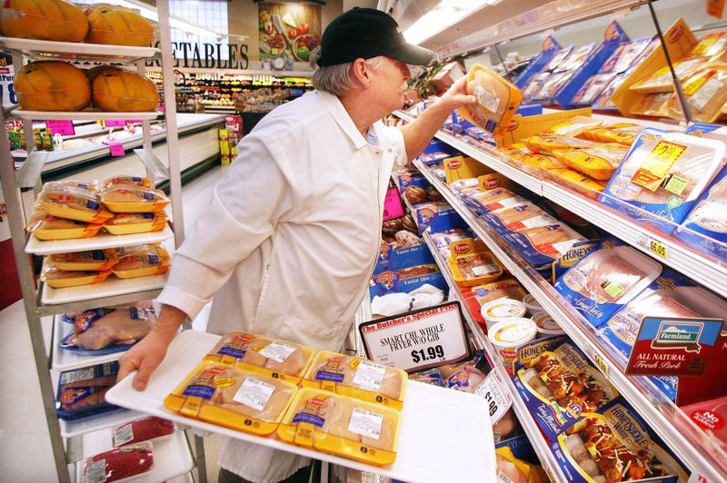 Gary Fuller, a meat cutter at Harps, stocks Tyson chicken products Monday at the grocery store on Colorado Drive in Fayetteville. 
