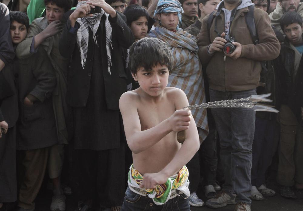 An Afghan Shiite boy beats himself with knives during a Muharram procession in Kabul, Afghanistan, Tuesday, Dec. 6, 2011. A suicide bomber struck a crowd of Shiite worshippers at a mosque in Kabul on Tuesday, killing at least 54 people in the deadliest of two attacks on a Shiite holy day, the first major sectarian assaults since the fall of the Taliban a decade ago. (AP Photo/Musadeq Sadeq)