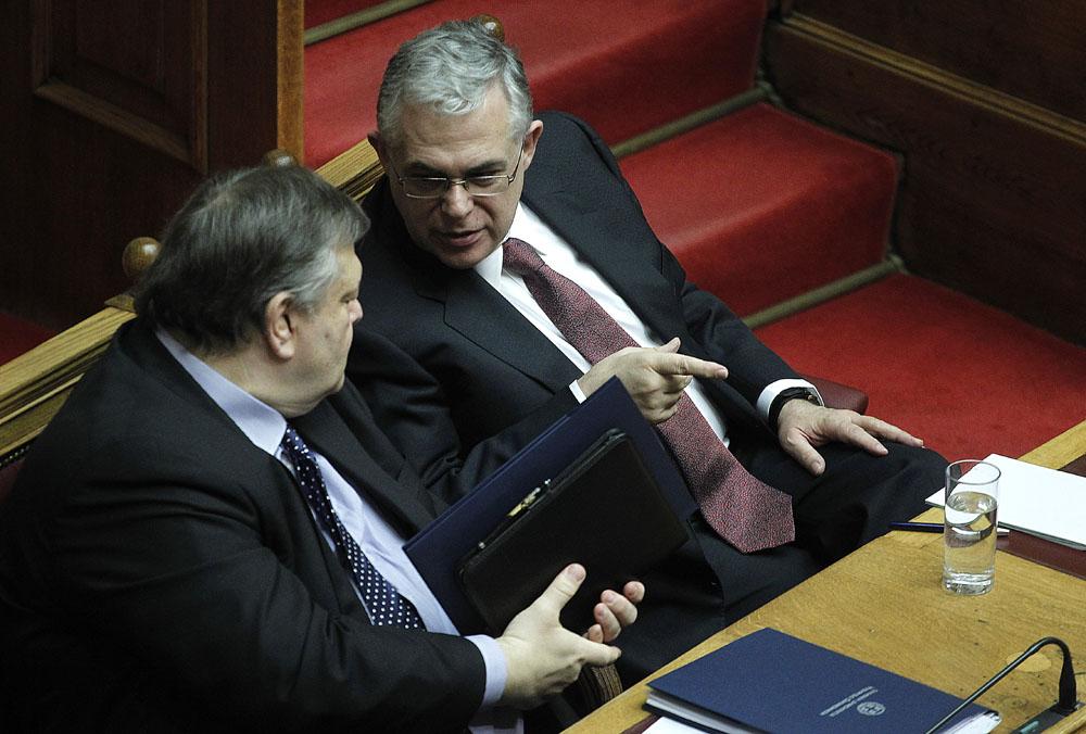 Greek minister of Finance Evangelos Venizelos, left, chats with Greek Prime Minister Lukas Papademos during a parliament session about the next year state budget, in Athens, on Tuesday, Dec. 6, 2011. Greece's lawmakers were set Tuesday to pass next year's austerity budget, extending tough spending cuts measures that have already left Greeks struggling as the country tries to slash its debts and pull itself out of a severe recession.(AP Photo/Petros Giannakouris)