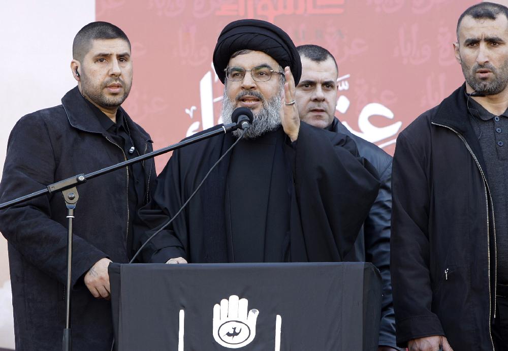 Hezbollah leader Sheik Hassan Nasrallah, center, flanked by his bodyguards, addresses the crowd in a rare public appearance during a rally to mark the Muslim holy day of Ashoura, in the Hezbollah stronghold of southern Beirut, Lebanon, Tuesday Dec. 6, 2011. Sheik Hassan Nasrallah made a rare public appearance at a Beirut rally on Tuesday to mark the Shiite holy day of Ashoura, saying his militant group is acquiring more weapons and members every day. (AP Photo/Bilal Hussein)