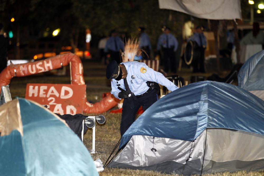 A New Orleans police officer checks a tent for people as they clear out the Occupy New Orleans encampment in Duncan Plaza across from City Hall in New Orleans on Tuesday, Dec. 6, 2011. (AP Photo/Gerald Herbert)
