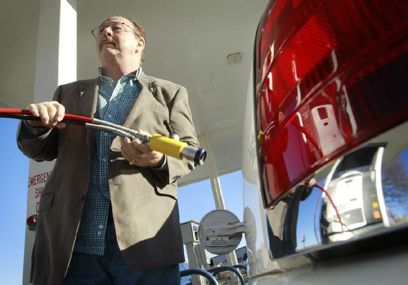 David Ricci, who owns a Ford Crown Victoria that runs on natural gas, holds a fueling hose Thursday at the natural gas filling station in North Little Rock. 