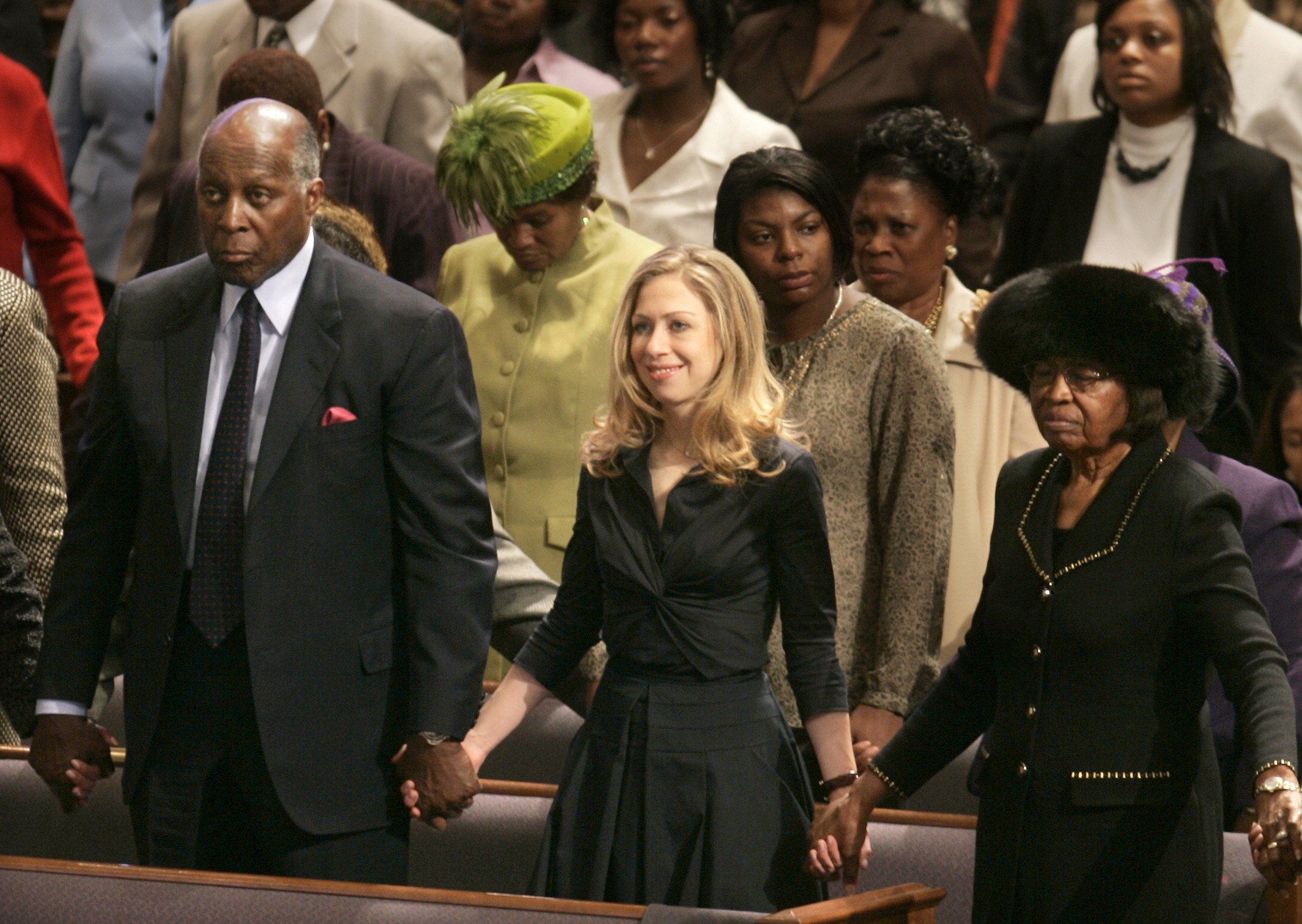 2008 | Chelsea Clinton holds hands with Vernon Jordan, left, and Jannie R. Jackson, right, while attending Bible Way Church of Atlas Road in Columbia, S.C.