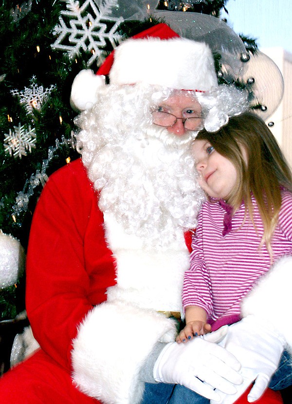 Tiffany von Ree of Gravette snuggled up to Santa Claus and after their visit during his stop-over at the Bank of Gravette following the Gravette parade she casually asked, "Where are the reindeer?" Santa's visit was sponsored by the Chamber of Commerce and dozens of children enjoyed having their pictures taken with the "jolly old fellow" last Saturday morning.
