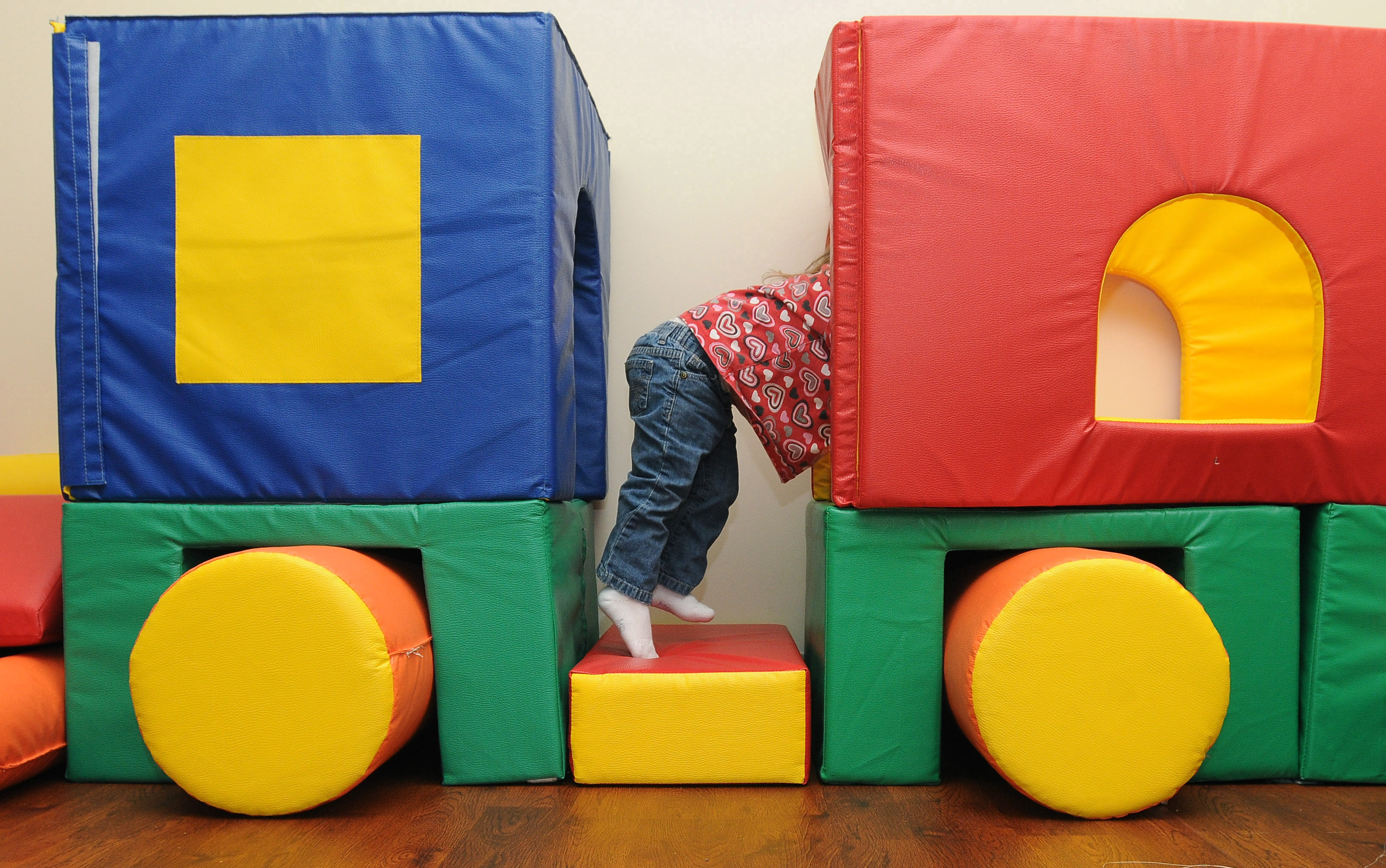 A two year old girl crawls across padded mats designed to look like a train Wednesday, Nov. 30, 2011, in the gross motor skills room at the Northwest Arkansas Children's Shelter.
