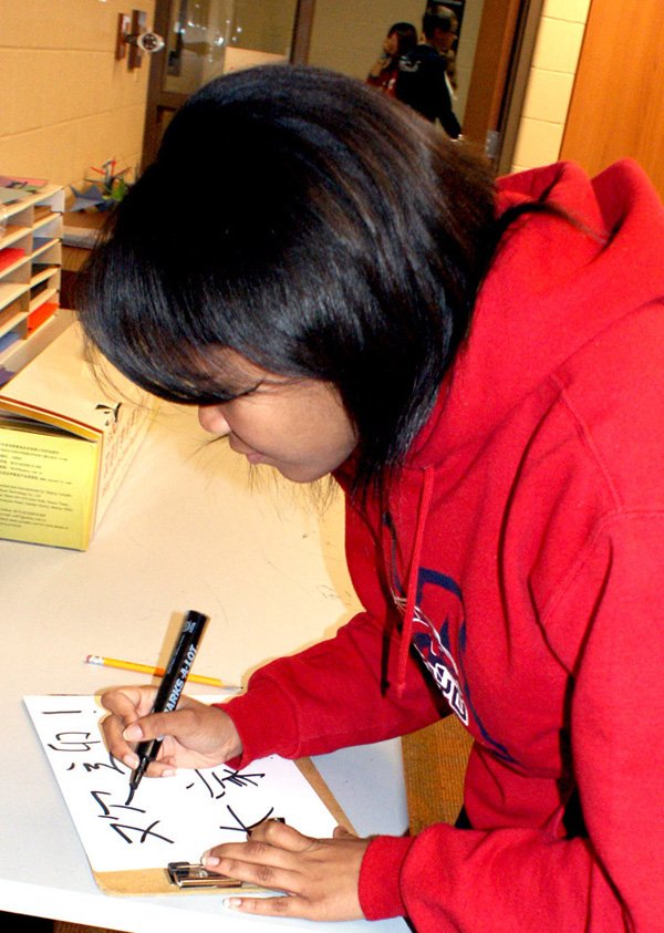 Tatiana Polydore, student in the Chinese II class at Gravette High, demonstrates by writing, "Welcome, Hello Everyone," in Chinese.