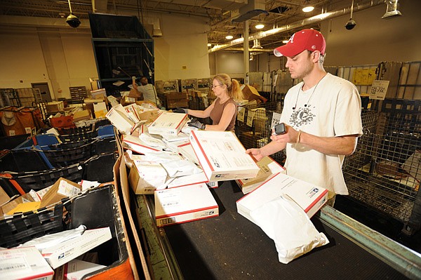 Andrew Davis, right, and Laura Curtis, processing clerks for the U.S. Postal Service, sort parcels on Dec. 22 at the facility in south Fayetteville.

