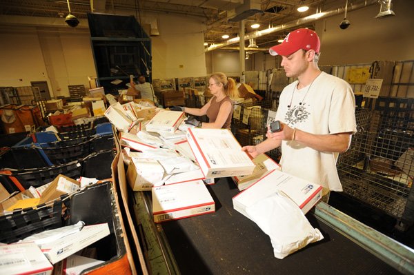 Andrew Davis, right, and Laura Curtis, processing clerks for the U.S. Postal Service, sort parcels on Dec. 22 at the facility in south Fayetteville.
