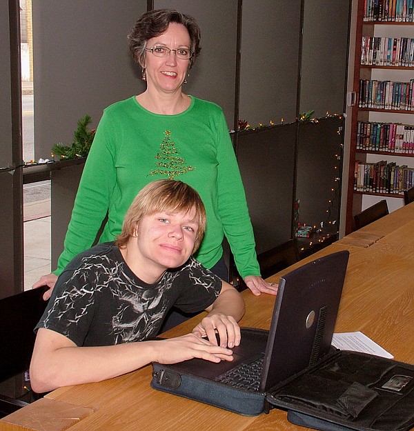 Joshua Harrington tries out a refurbished laptop computer at the Gentry Public Library on Dec. 22 while Gentry librarian Darla Threet looks on.