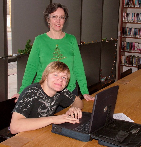 Joshua Harrington tries out a refurbished laptop computer at the Gentry Public Library on Dec. 22 while Gentry librarian Darla Threet looks on.