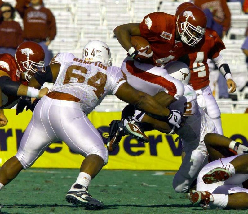 FILE — Arkansas running back Cedric Cobbs jumps over Texas defenders Casey Hampton (64) and Montrell Flowers in the 2000 Cotton Bowl, a 27-6 Razorbacks’ victory. 