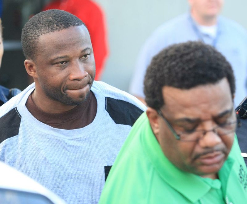 Little Rock police detective Terrell Vaughn (right) escorts Henry Harmon, who was charged Friday in the city’s third slaying of the year and an unrelated robbery. 