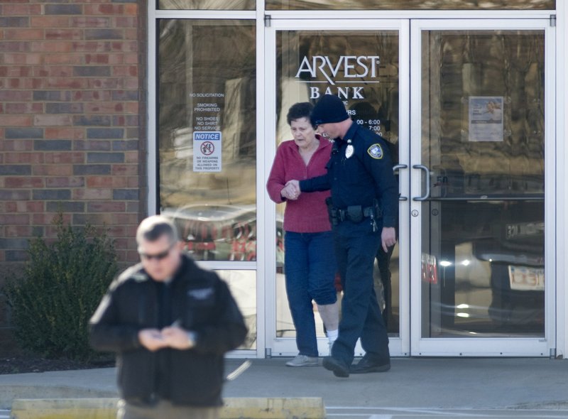 Betty Davis, 73, is led out of the Arvest Bank on Monday on Martin Luther King Jr. Boulevard in Fayetteville after the police and bomb squad were called to the bank after the woman reported she had been kidnapped and a bomb had been strapped to her ankle. She was led out of the bank after the device had been removed.
