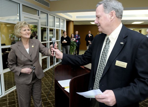 Becky Paneitz, president of NorthWest Arkansas Community College, hands the microphone to Scott Linebaugh, executive director of Youth Bridge, during an announcement Wednesday of $5,000 worth of scholarships from the NWACC President’s Circle to Youth Bridge at the Center For Nonprofits in Rogers.