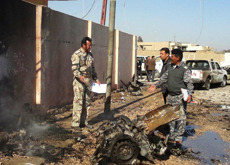 Iraqi security forces inspect the scene of a car bomb attack in front of a government compound in Ramadi, 70 miles west of Baghdad, Iraq, Sunday, Jan. 15, 2012. 