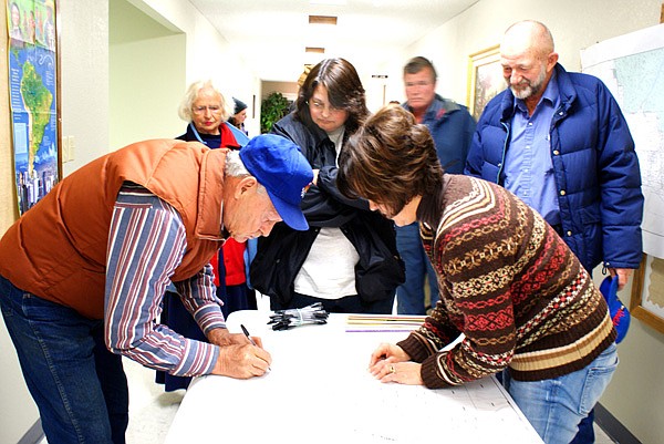 James Adams of Hiwasse signs a document indicating his willingness to be annexed into the City of Gravette rather than becoming part of Bella Vista which is hoping to annex Hiwasse area into that city. Shannon Mitchell showed proposed maps to Adams and others who were considering the plan which was explained at a meeting Thursday night at the Baptist Church in Hiwasse.
