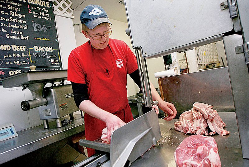 Shane Halvorson, a butcher at Richard’s Country Meat Market in Fayetteville, cuts meat on Wednesday. 