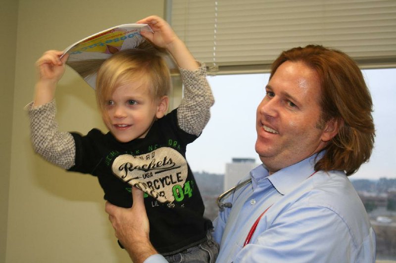 Liam Sanders, 3, holds a book given to him by Dr. Chad Rodgers of the Little Rock Pediatric Clinic. The clinic participates in the Reach Out and Read program, which is designed to promote literacy by dispensing free books to children during well-child visits to the doctor. 