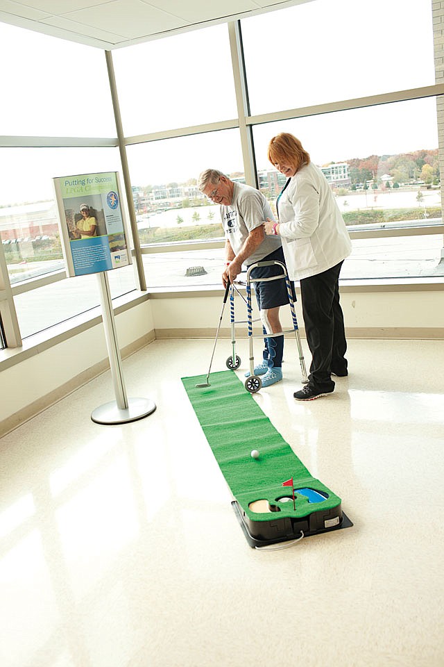 The Joint Replacement Center’s program coordinator, Karen Tanner, helps a patient play golf, which is part of group therapy.