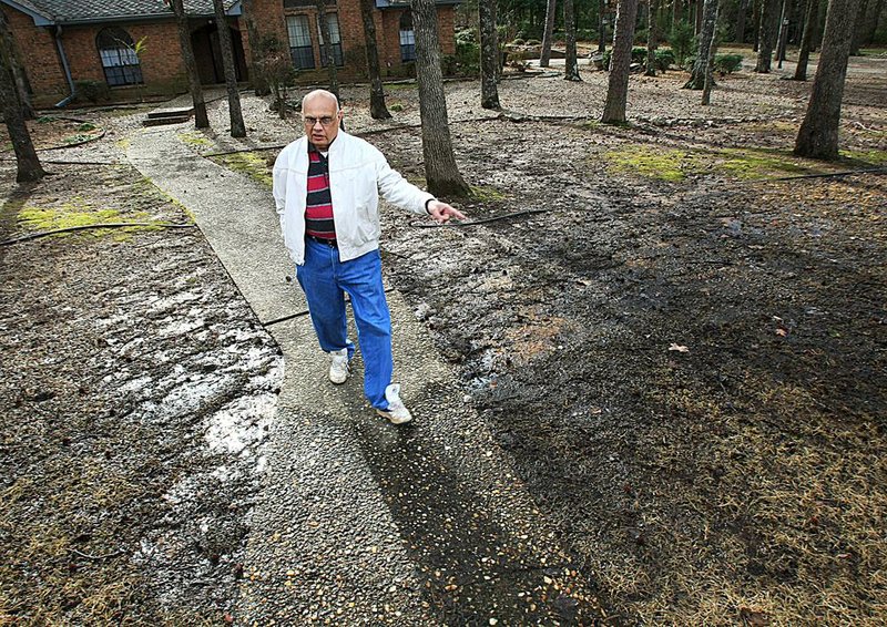  Dr. Dileep Vyas walks down the walkway in front of his west Little Rock home Saturday morning as standing water fills part of his yard from rain earlier in the week. The city has proposed drainage improvements for the neighborhood where Vyas lives. 