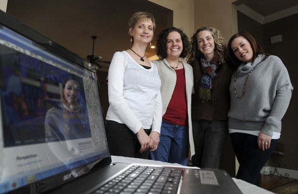 Melissa Pope, from left, Jennifer Mullen, Kerri Young and Gretchen Speer stand together at Pope’s home in Little Flock on Jan. 22 as a computer displays their faith-based blog, mosaicofmoms.com.
