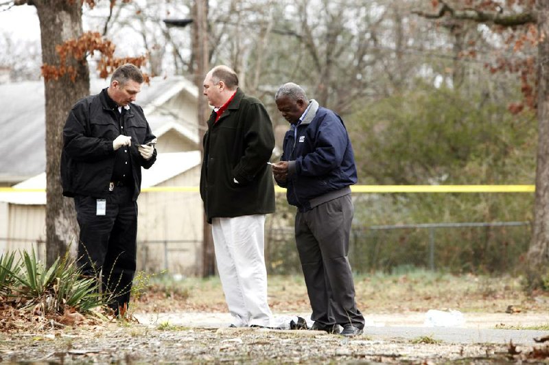 Little Rock police detectives examine items found near where Antonio Nelson, 29, of 2105 S. Valentine St. was shot and killed Wednesday afternoon near 19th and South Brown streets. It was the eighth homicide in the city this year. 