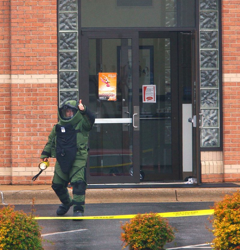 Little Rock Fire Department bomb technician Ryan Baker signals Friday to other bomb-squad members that they can approach a U.S. Bank branch after a bank robber left a backpack containing what he said was a bomb in the building’s doorway. No explosives were found. 