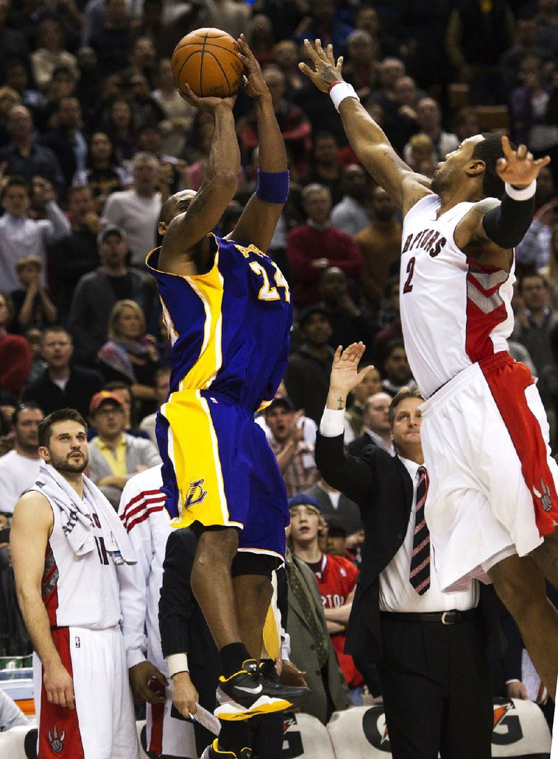 Los Angeles Lakers guard Kobe Bryant (front left) makes the game-winning jump shot over Toronto Raptors forward James Johnson in the Lakers’ 94-92 victory Sunday. 