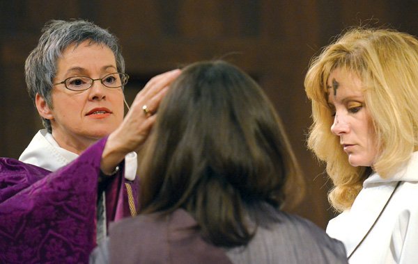 The Rev. Suzanne Stoner places ashes on the forehead of Deacon Emily Bost and acolyte Christine Cook as they participate in an Ash Wednesday service at St. Paul’s Episcopal Church in Fayetteville.
