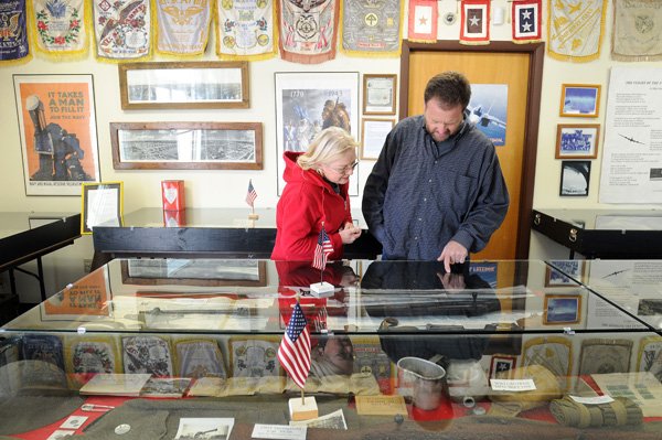 Deborah Ramsey, left, and Brian McCarley look at World War II artifacts Monday in the Ozark Military Museum in Fayetteville. The museum plans to merge into a single nonprofit entity with the Arkansas Air Museum.