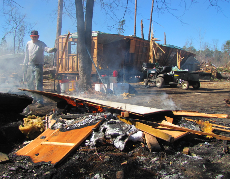 Bennie Cox works to dismantle and burn a trailer that was destroyed in a Jan. 22 tornado in Fordyce.