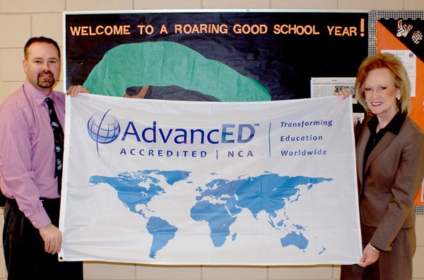 A banner, recognizing Gravette schools' achievement as AdvancED Accredited by ACE, is held by Glenn Duffy Principal Zane Vanderpool and Gravette School superintendent Andrea Kelly. All four Gravette schools received AdvancED accreditation and framed certificates are displayed in each school office.