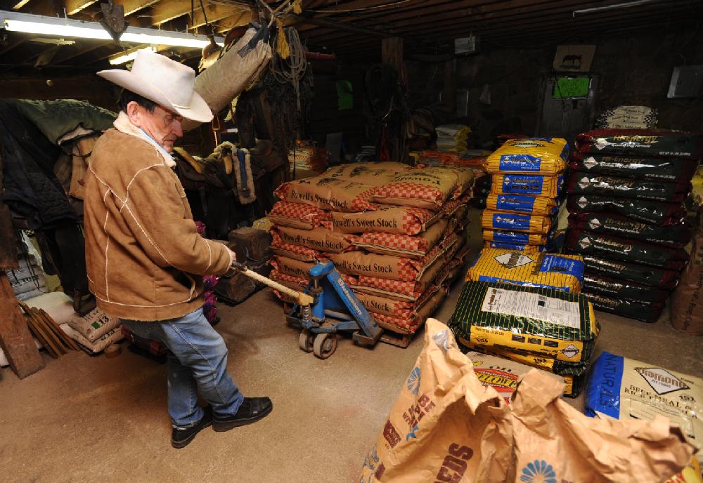 STAFF PHOTO ANDY SHUPE
Neil Mathews, 81, works Tuesday, Feb. 21, 2012, to fill an order for a customer inside the storeroom of the Mathews Horse and Feed Barn which he operates with his son in West Fork.