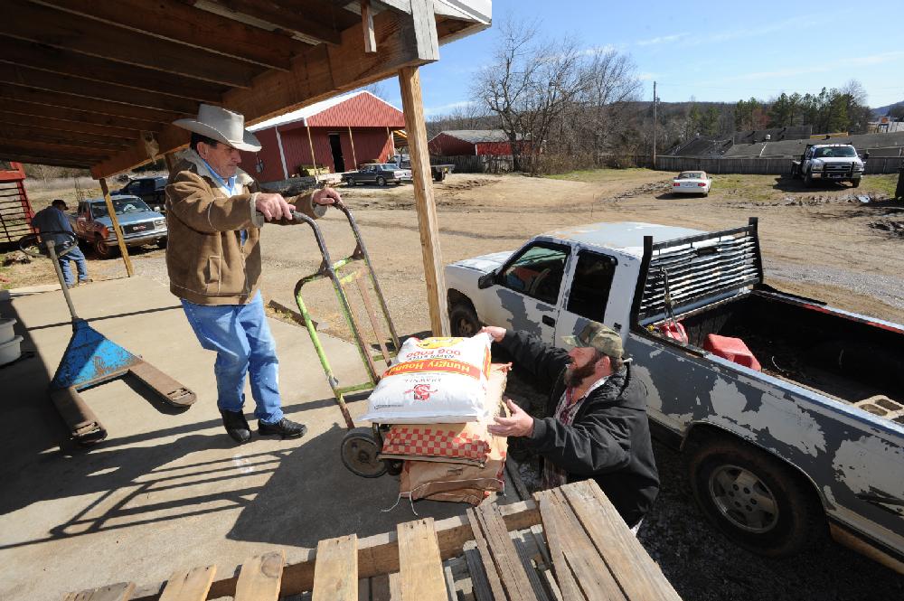 STAFF PHOTO ANDY SHUPE
Neil Mathews, 81, left, works Tuesday, Feb. 21, 2012, to load an order for a customer with help from his son, Tony, right, on the loading dock of the Mathews Horse and Feed Barn which they operate in West Fork.