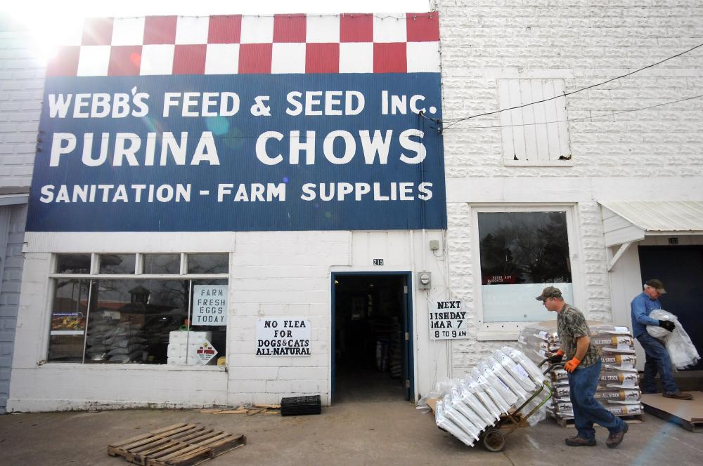 STAFF PHOTO MARC F. HENNING
Aaron David, left, and Doug McKinney work to move a new shipment of livestock feed Wednesday, Feb. 22, 2012, inside of Webb's Feed and Seed Inc. in downtown Pea Ridge. McKinney, son of store owner Fred McKinney, has been working at Webb's for 50 years. David has worked at the store since his senior year in high school, 20 years ago. Webb's celebrated it's 75th anniversary on Sept. 30.