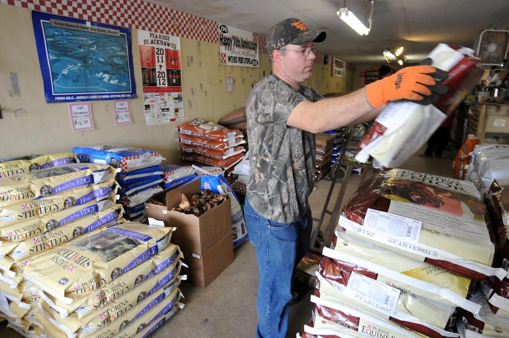 STAFF PHOTO MARC F. HENNING
Aaron David stocks bags of feed from a new shipment Wednesday, Feb. 22, 2012, inside Webb's Feed and Seed Inc. in downtown Pea Ridge. David has worked at the store since his senior year in high school, 20 years ago.