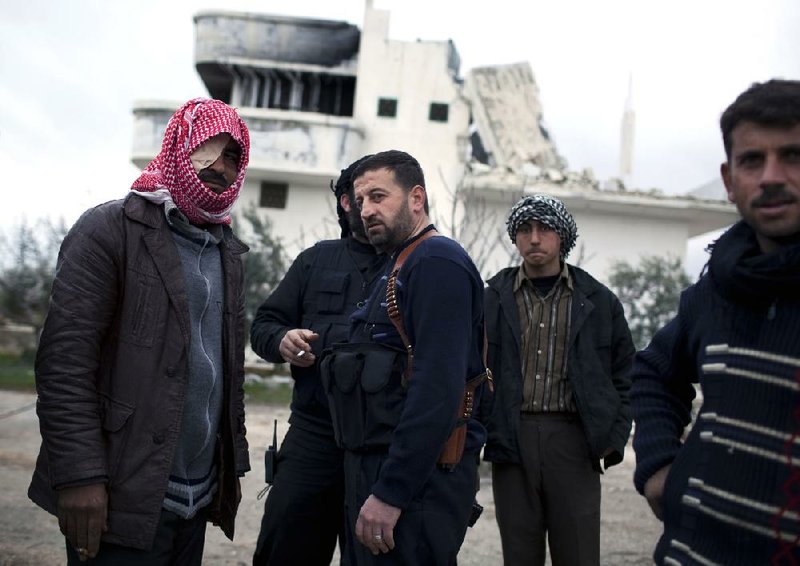 Syrian rebel soldiers gather outside a destroyed house in Sarmin in northern Syria on Tuesday after battling government forces. 