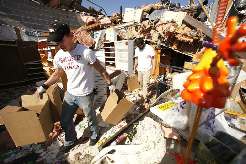 Tim Thress (left) of Branson and Wake Williams of Omaha, Ark., help out at a friend’s store Wednesday in Branson. The storm hit some of the city’s signature tourist venues. 