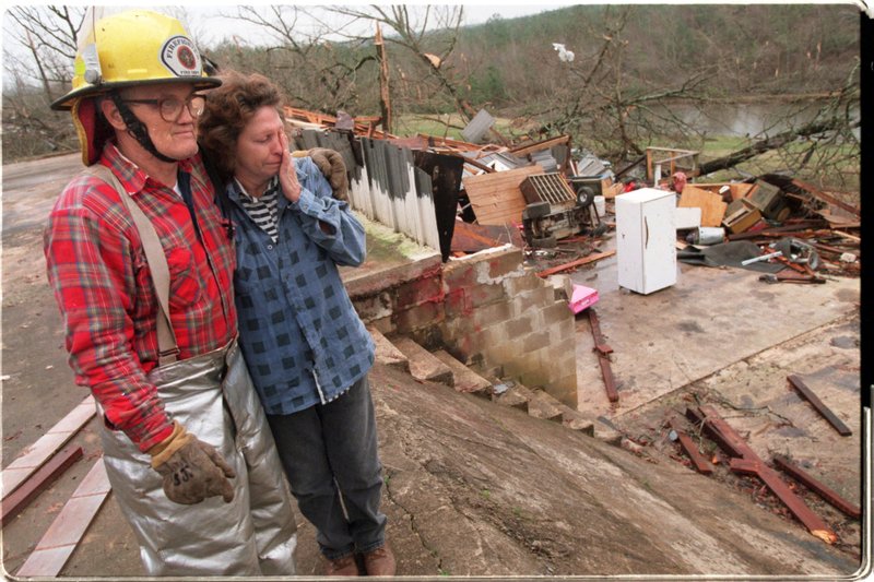 Volunteer fireman Sydney Jobe consoles his friend Lou Herdon, who can't hold back her tears as see looks over the damage done to her property at 13303 Pine Ridge Road.